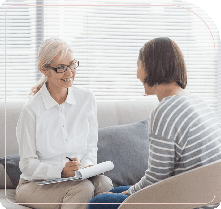 A woman sitting on the couch talking to another person.